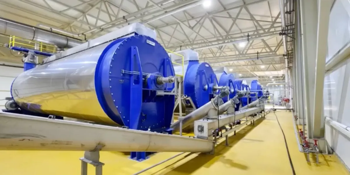 A row of blue rotary drums in a processing hall